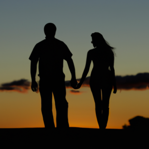 A romantic couple silhouetted against a sunset sky, holding hands.