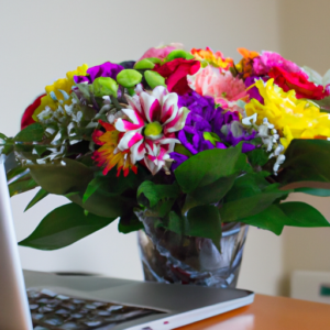 A colorful bouquet of flowers with a laptop in the background.