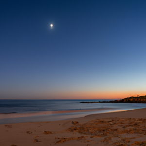 A beach with a crescent moon in the background.