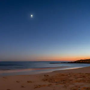 A beach with a crescent moon in the background.