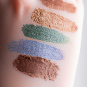  A close-up of a hand with colorful mineral makeup swatched across the skin.